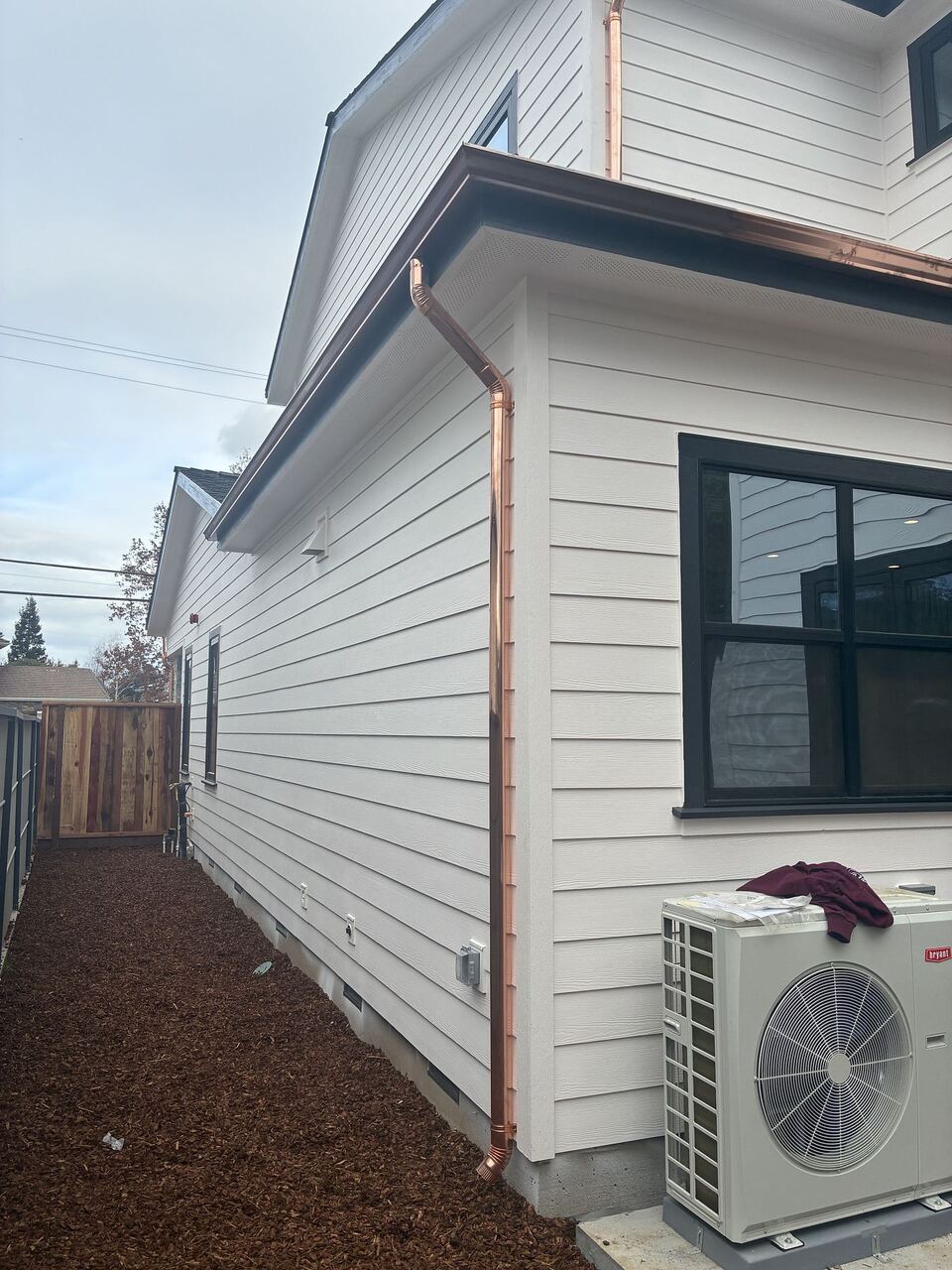 Full copper downspout run along side elevation with white lap siding