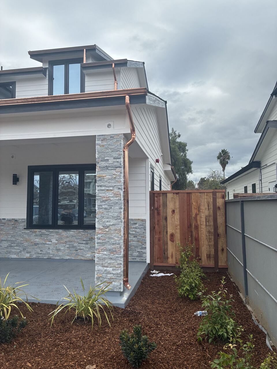 Copper downspout against stacked stone column at front porch