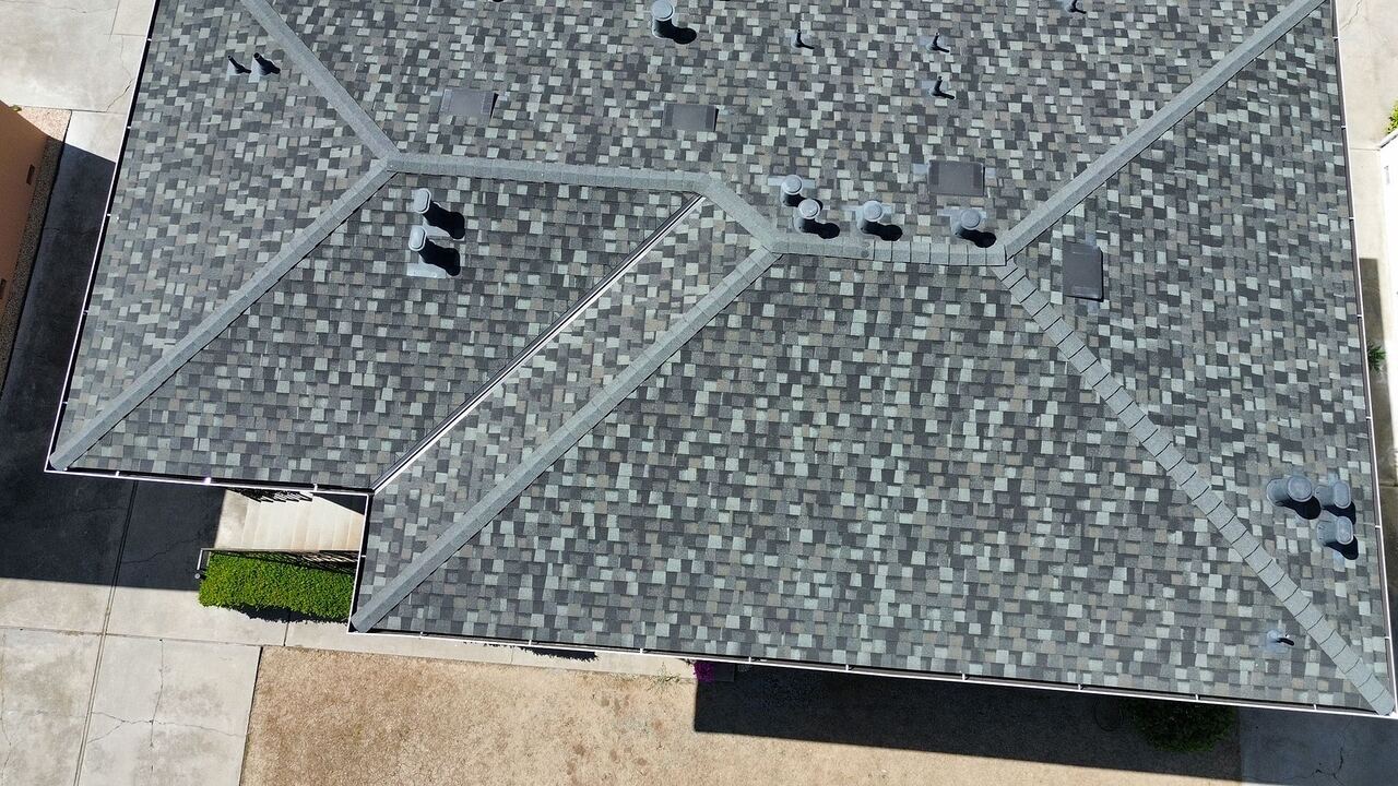 Top-down detail of Landmark shingle roof showing ridge cap, hip transitions, and color-matched vent stacks