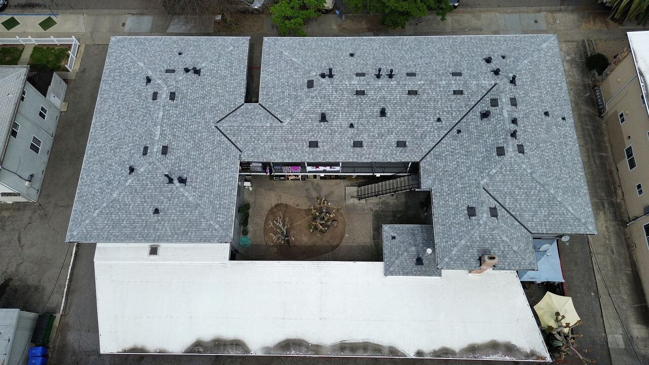 Wide aerial showing the full scope of the project — Landmark shingle on pitched wings and single-ply on flat carport deck