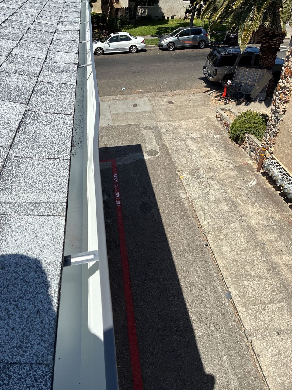 New continuous seamless aluminum gutter run viewed from roof level above the apartment building