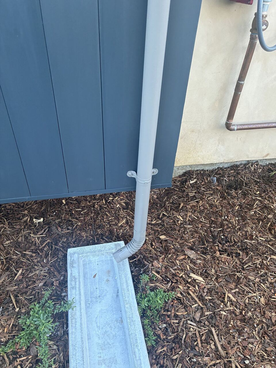 Downspout terminating into concrete splash block to direct rainwater from foundation